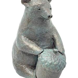 Sculpture of a whimsical friendly bear sitting with a large acorn in front of him with a bronze patina finish by Karin Taylor.