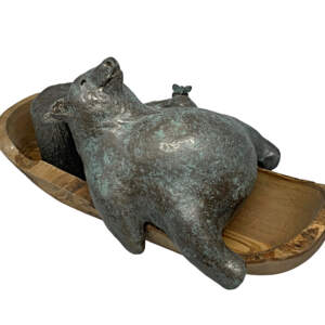 Mixed media sculpture by Karin Taylor of a friendly bear laying in a wooden kayak with a butterfly in in hand.