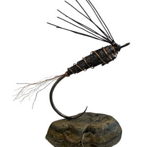 Steel and copper metal fly fishing sculpture on a grey rock by Paul Reimer.